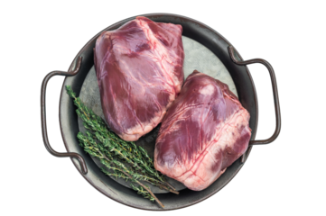 Whole pork  hearts revealing natural color detail and vascular lines set on round metal tray with herbs on light background.