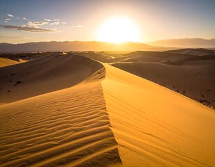 Sunrise illuminates desert dunes, a warm glow over distant mountains