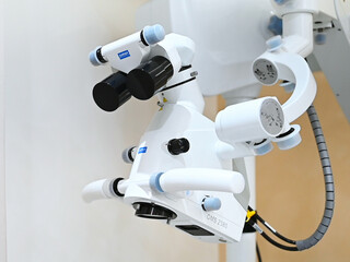 A detailed shot of a Zumax OMS 2380 dental operating microscope with its adjustment knobs and binoculars