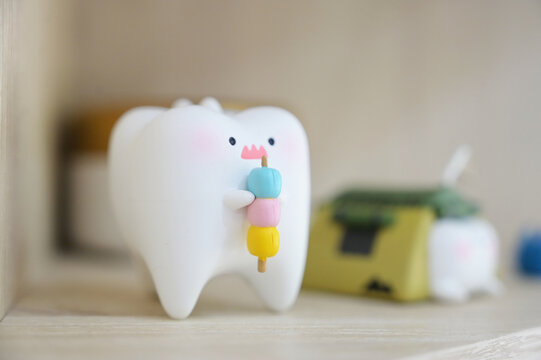A small tooth figurine holding colorful dango, shown in a close-up on the display shelf