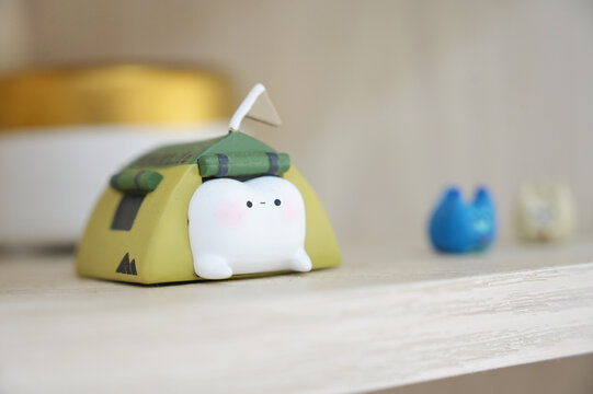 A tooth figurine peeking out from a miniature camping tent, displayed as part of the clinic&rsquo;s d&eacute;cor