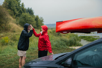 Senior couple high fiving enjoying rainy kayaking adventure