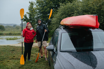 Senior couple enjoying rainy kayaking adventure with paddles
