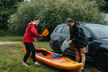 Senior couple preparing kayak for a rainy adventure