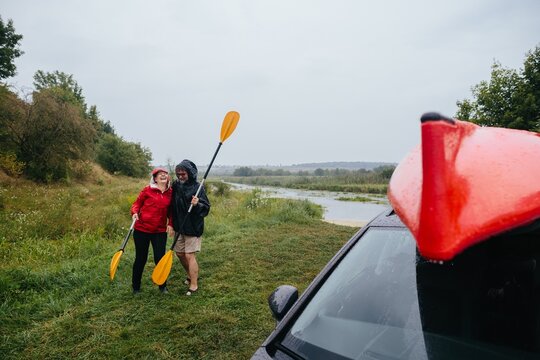 Senior couple enjoying outdoor kayaking adventure in rain - Powered by Adobe