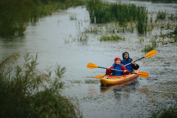 Senior couple actively kayaking together in the rain