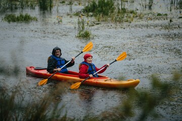 Mature couple kayaking together enjoying rainy outdoor adventure