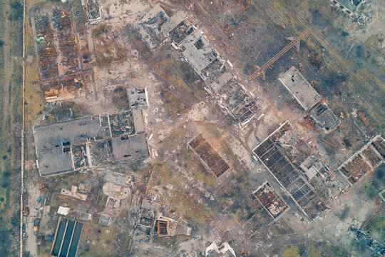 Aerial top down view of completely destroyed city buildings and industrial ruins. War invasion aftermath and apocalyptic urban infrastructure texture.