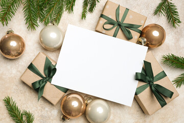 Christmas greeting card mockup with blank space for personalized message surrounded by beautifully wrapped gift boxes and festive ornaments on a textured background