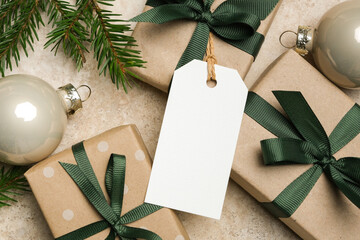 Christmas gift tag mockup with blank space, surrounded by beautifully wrapped gift boxes and ornaments, creating a festive holiday atmosphere for design purposes