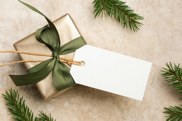 Christmas gift tag mockup with elegant gift box wrapped in gold ribbon, surrounded by fresh pine branches, perfect for holiday design projects and festive celebrations