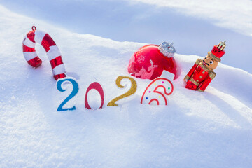 Candles - numbers, and Christmas tree decorations are buried in white snow and form the inscription 2026. The concept of New Year and Christmas