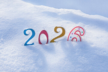 Paraffin candles - numbers sink into the snow and spell out the inscription 2026. A symbol of the approaching Christmas and New Year