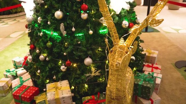 A close-up view of a beautifully decorated Christmas tree featuring silver, red, and green ornaments, sparkling snowflake decorations, and warm festive lighting. The rich green branches