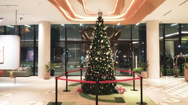 A close-up view of a beautifully decorated Christmas tree featuring silver, red, and green ornaments, sparkling snowflake decorations, and warm festive lighting. The rich green branches