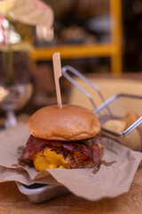Gourmet pulled pork burger with bacon and melted cheese on craft paper in a modern restaurant, perfect for menu design, delivery ads, street food branding and social media content.