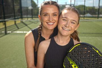 Two padel tennis players with rackets. Woman and girl teenager athlete with paddle racket on court outdoors. Sport concept. Download a high quality photo for the design of a sports app or web site.