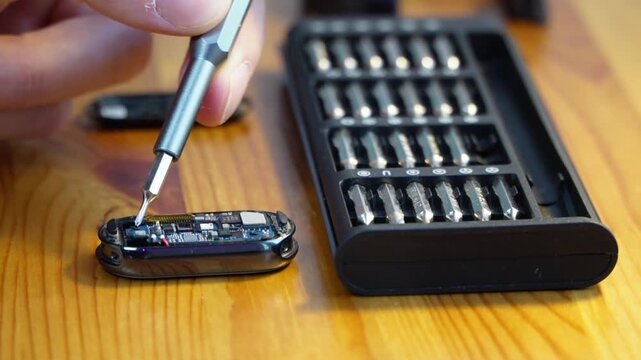 close up of a mans hand repairing a complex small electronic device with a precision screwdriver kit symbolizing modern technology research development technical diagnostics maintenance and science