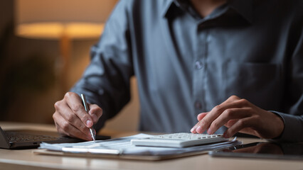 A person reviewing financial documents and using a calculator to manage monthly budgeting and expenses. Finance concept. Monthly finance planning. Financial lifestyle concept.