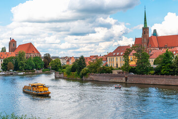 Scenic view of river odra with yellow boat and historic architecture in wroclaw