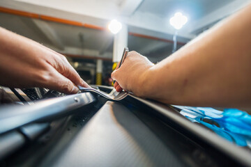 Detail of a worker's hand cutting self-adhesive foil on the hood of a car. The process of installing stickers on a sports car.