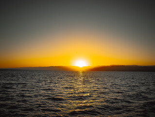 Naklejka premium Sunset over the Red Sea in Aqaba with golden sky and shimmering water