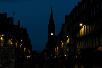 Fototapeta premium Night street scene on the Royal Mile in Edinburgh with illuminated clock tower