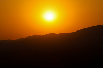 Obraz premium Golden sunset over mountain silhouettes with bright orange sky