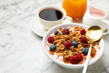 Tasty breakfast. Granola with yogurt and fruits served on white marble table, closeup. Space for text
