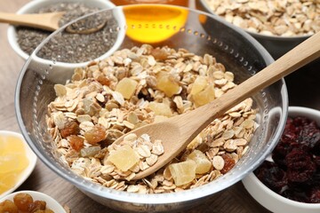 Making granola. Oat flakes with dried fruits in bowl on wooden table, closeup