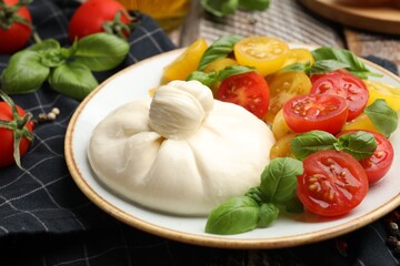 Delicious burrata cheese with basil and tomatoes on wooden table, closeup