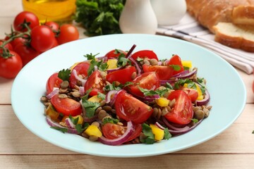 Delicious salad with lentils and vegetables on light wooden table, closeup