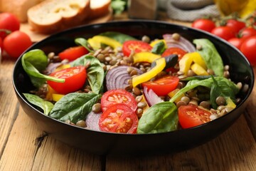 Tasty salad with lentils and vegetables on wooden table, closeup