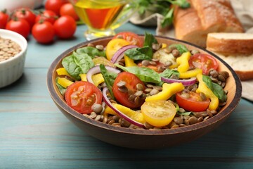 Tasty lentil salad, ingredients and bread on light blue wooden table, closeup