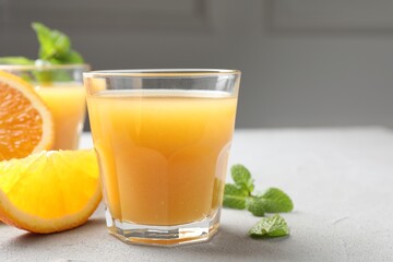 Fresh orange juice, mint and fruits on light table, closeup. Space for text