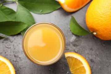 Fresh orange juice, fruits and leaves on grey table, flat lay
