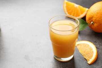 Fresh orange juice and fruits on grey table, closeup. Space for text