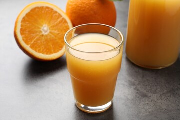 Fresh orange juice and fruits on grey table, closeup