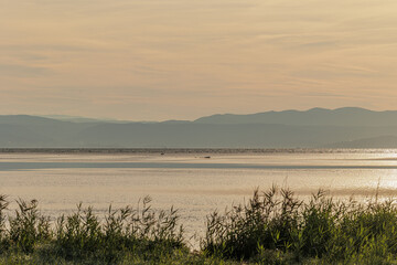 vista dettagliata che si estende dalla costa della citt&agrave; di Grado verso la sponda opposta della citt&agrave; di Trieste e le colline della Slovenia lontane, di giorno, con cielo leggermente nuovoloso