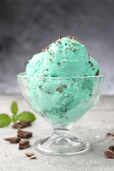 Tasty mint chocolate chip ice cream on grey textured table, closeup
