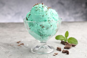Tasty mint chocolate chip ice cream on grey textured table, closeup