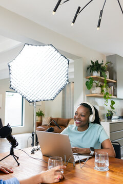 African American woman recording at home under softbox with headphones and microphone, copy space