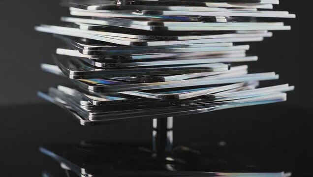 A close-up shot of a stack of CDs on a dark background, reflecting light and creating a sense of depth and mystery.