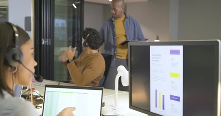 After placing headset diverse coworkers handling support calls celebrating charts at open office - Powered by Adobe