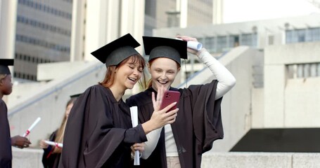 Diverse female graduates extending phone, starting call for graduation waving diplomas on plaza