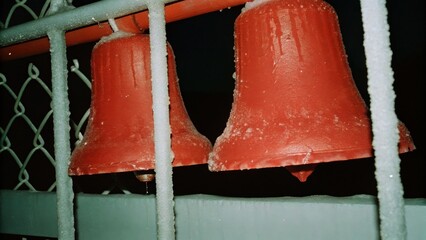 Dark Chirstmas Two red bells covered in frost against a dark background.