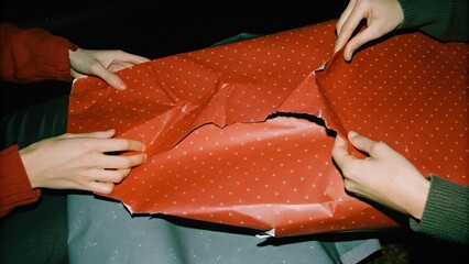 Dark Chirstmas People unwrapping a red, polka-dotted gift wrapper.