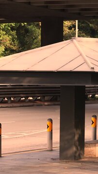 Empty bus stop with triangular roof near elevated highway pillars in city scene
