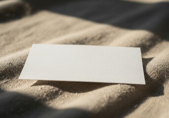 Blank card on soft fabric with warm natural shadows 