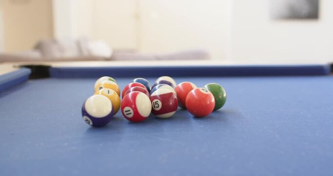 Unseen cue ball is striking clustered pool balls, scattering them on blue-felt table to start game